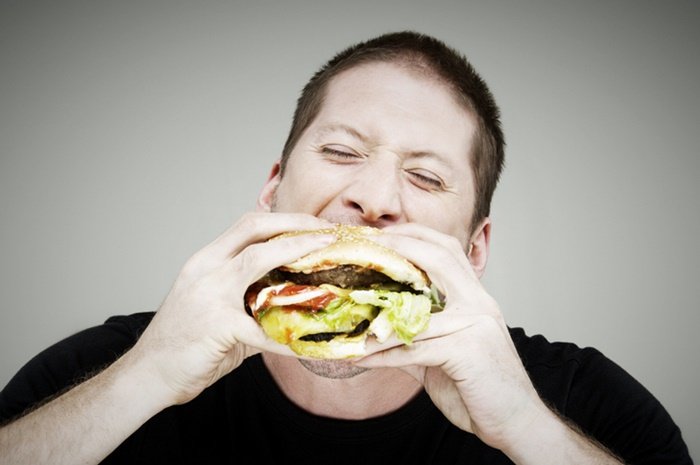 Homem comendo hambúrguer - Metrópoles