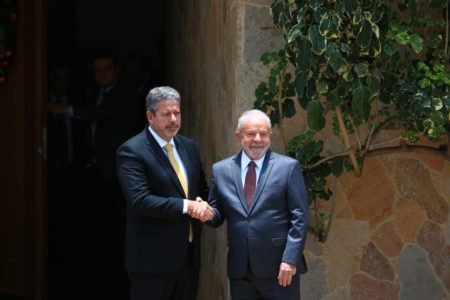 O presidente da Câmara dos Deputados, Arthur Lira, aperta a mão do presidente eleito Lula. Ambos olham para a câmera e sorriem, na porta da residência oficial do presidente da casa legislativa- Metrópoles
