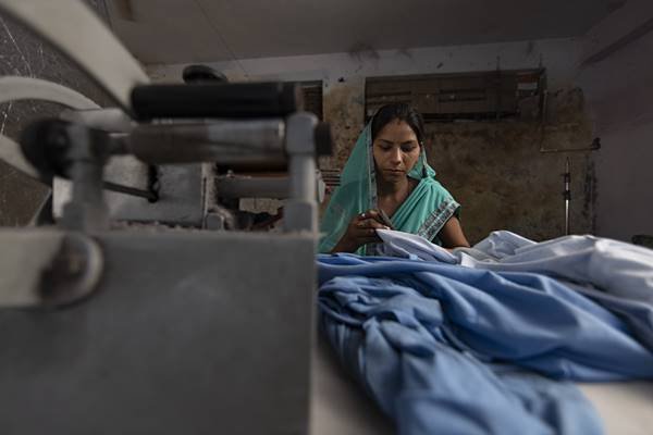 Mulher em fábrica na índia costurando - Metrópoles 