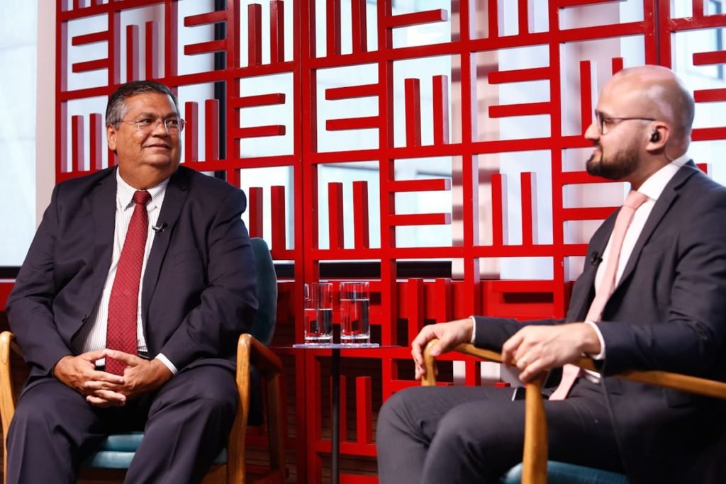 Senador eleito pelo Maranhão, Flávio Dino, dá entrevista ao Metrópoles ao lado do jornalista Igor Gadelha. Ambos se olham, sorrindo - Metrópoles