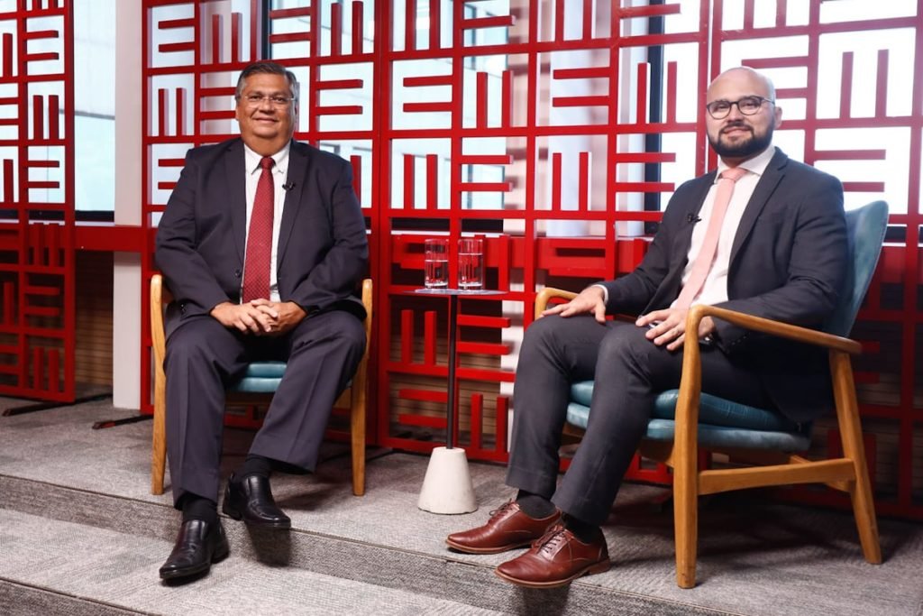Senador eleito pelo Maranhão, Flávio Dino, dá entrevista ao Metrópoles ao lado do jornalista Igor Gadelha. Ambos olham para a câmera, sorrindo - Metrópoles