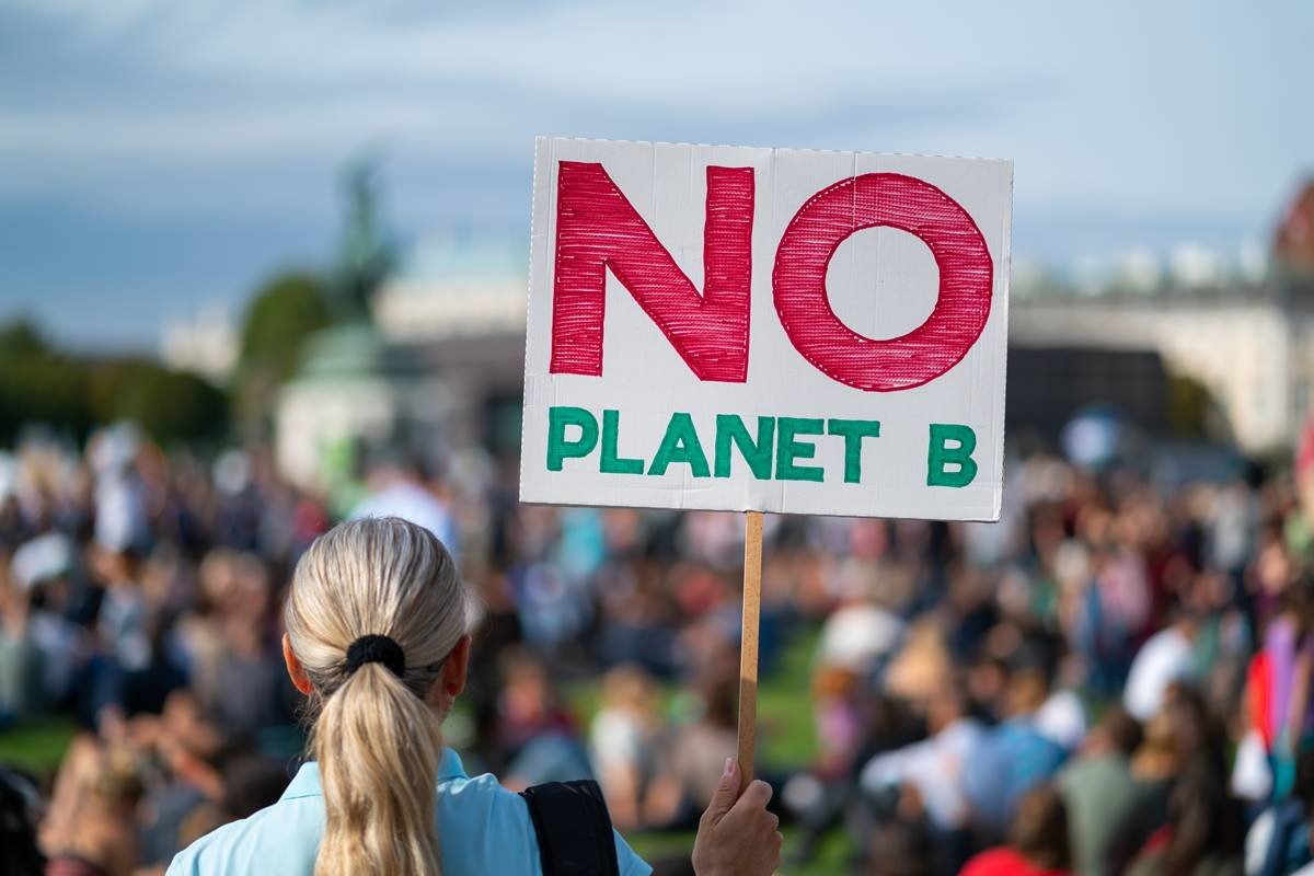Mulher em protesto erguendo placa "Não há planeta B* - Metrópoles