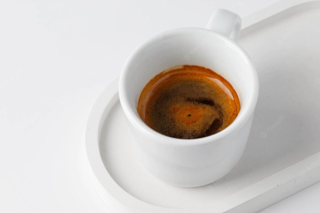 Na imagem, uma xícara branca com café dentro em um fundo branco - Metrópoles