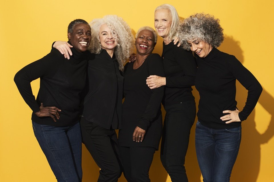 Foto colorida de cinco mulheres negras e brancas abraçadas - Metrópoles