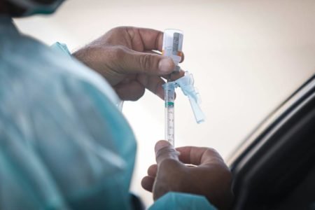 Mãos segurando seringa com vacina