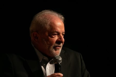 Imagem colorida mostra Luiz Inácio Lula da Silva, presidente eleito, em pé em um palco. Ele usa terno e segura um microfone - Metrópoles