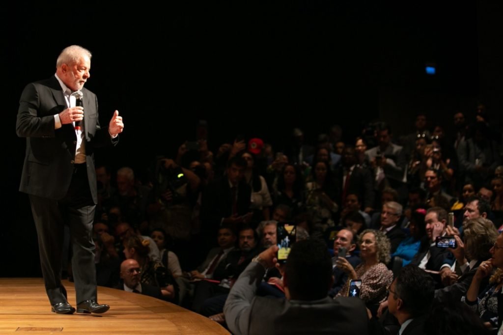 Imagem colorida mostra Luiz Inácio Lula da Silva, presidente eleito, em pé em um palco. Ele usa terno e segura um microfone - Metrópoles