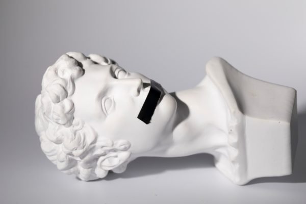 Escultura de rosto com fita preta cobrindo a boca - Metrópoles