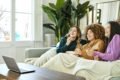 Três mulheres sentadas no sofá assistindo filme no computador - Metrópoles