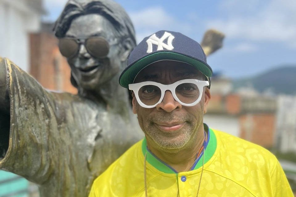 O cineasta norte-americano Spike Lee, com a camisa da seleção brasileira, posa ao lado da estátua de Michael Jackson no Morro Dona Marta (RJ) - Metrópoles
