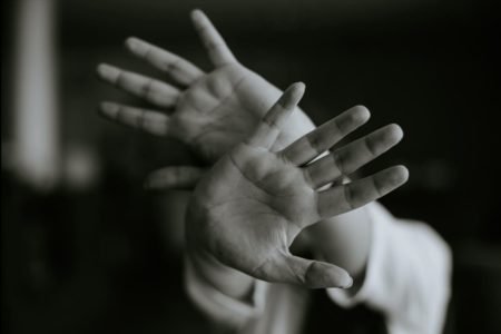 Imagem preta e branca de mãos de uma mulher que tenta impedir ataque