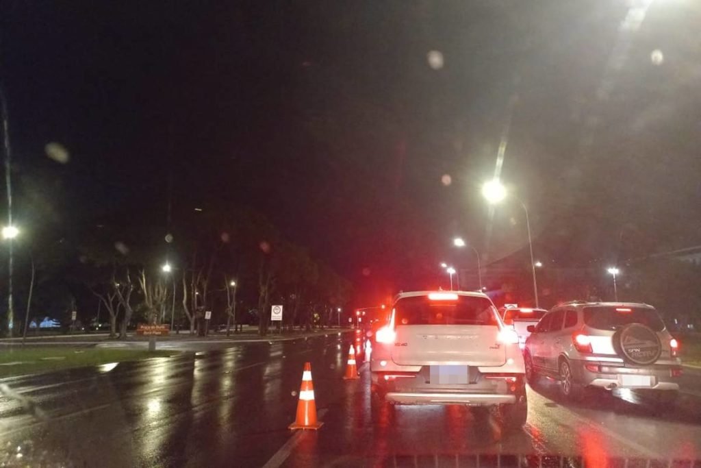 Carro branco parado ao lado de cone