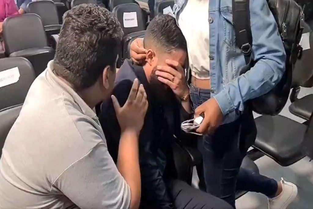 Homem chorando é consolado por amigos
