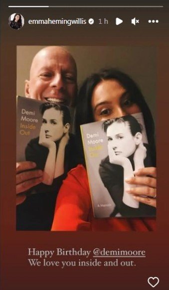 Bruce Willis e a esposa segurando a biografia de Demi Moore - Metrópoles