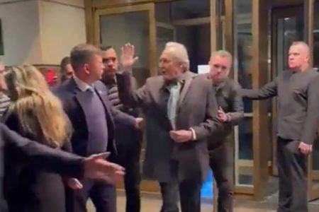 Imagem colorida mostra ministro RIcardo Lewandowski, do STF, saindo de um hotel. Ele é cercado por seguranças e perseguido por manifestantes / Metrópoles