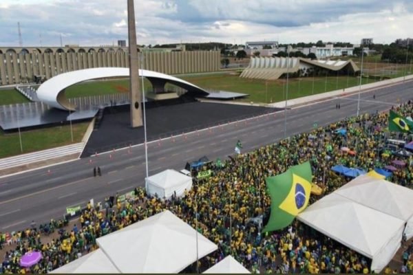 Fotografia colorida do alto mostra manifestantes de verde e amarelo e grande bandeira do Brasil