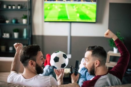 Dois homens no sofá assistindo futebol na TV-Metrópoles