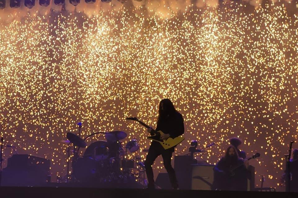 Foto de palco com banda e ao fundo cascata de fogos de artifício - Metrópoles