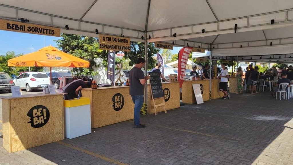 Foto de uma área aberta coberto por uma tenda branca e várias balcões feitos de madeira