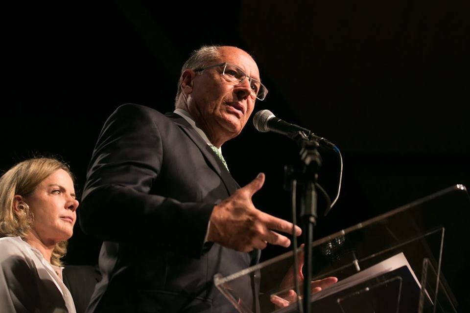 Imagem colorida do coordenador da transição e vice-presidente eleito, Geraldo Alckmin, anuncia mais nomes pra transição do novo governo. Ele fala em púlpito ao lado da presidente do PT, Gleisi Hoffmann - Metrópoles