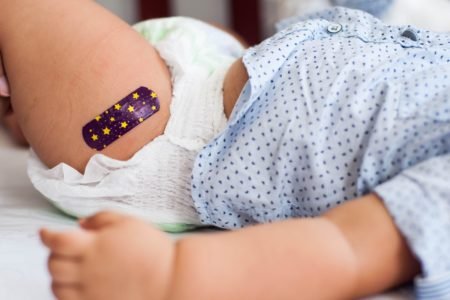 perna de bebê de fralda com curativo depois da vacinação - Metrópoles