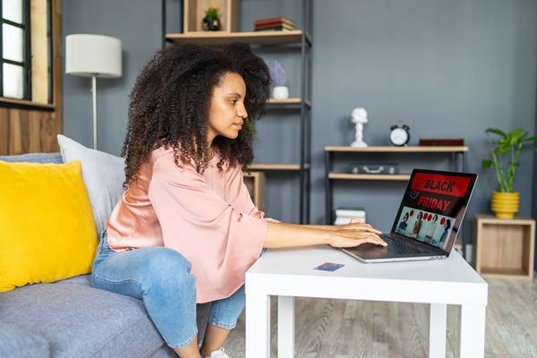 Mulher usando o laptop com um anúncio da Black Friday - Metrópoles 