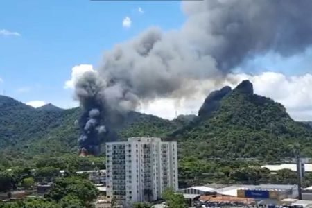 Incêndio atinge Projac, da Globo, no Rio de Janeiro. É possível ver muita fumaça saindo do meio de uma mata em morro, próximo a prédios - Metrópoles