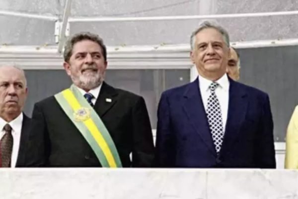 Imagem colorida dos presidente Lula e Fernando Henrique Cardoso no dia da posse de Lula. Esse usa a faixa presidente e ambos sorriem, de cima do Planalto - Metrópoles