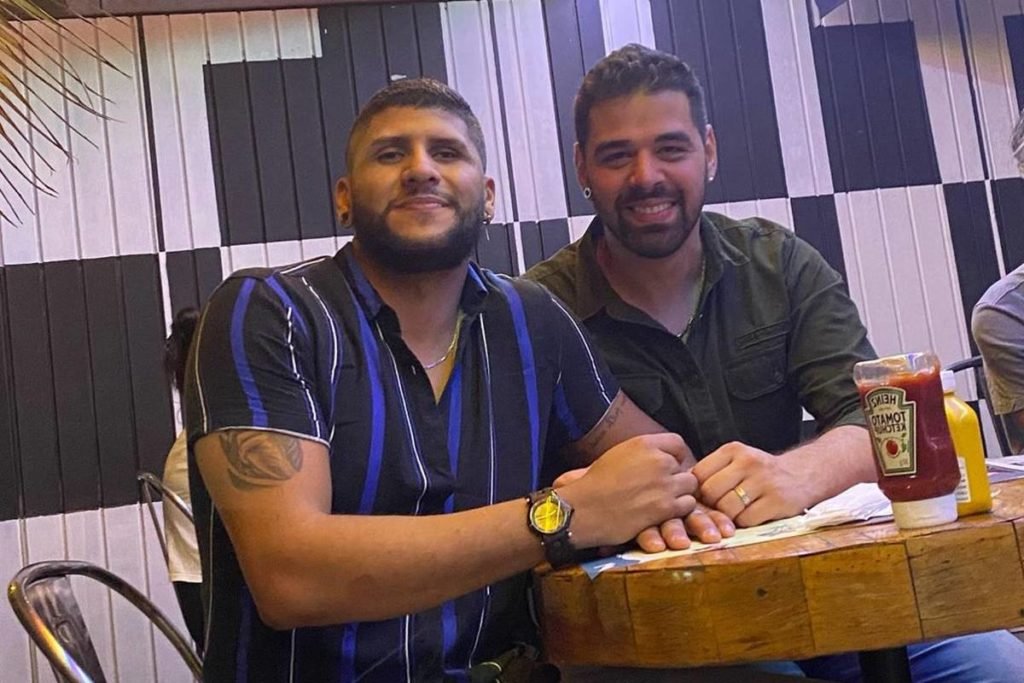 dois homens sentados em mesa - Metrópoles