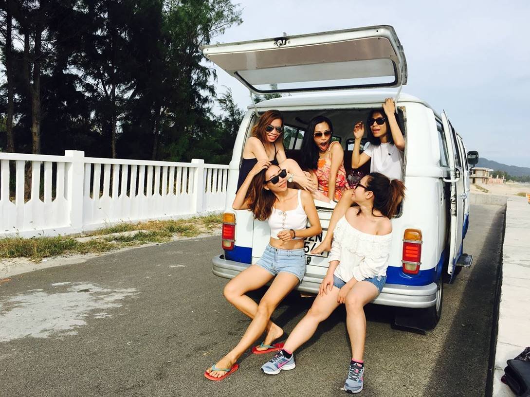 Amigas sentadas na parte de trás de um carro kombi enquanto conversam em uma lugar praiano