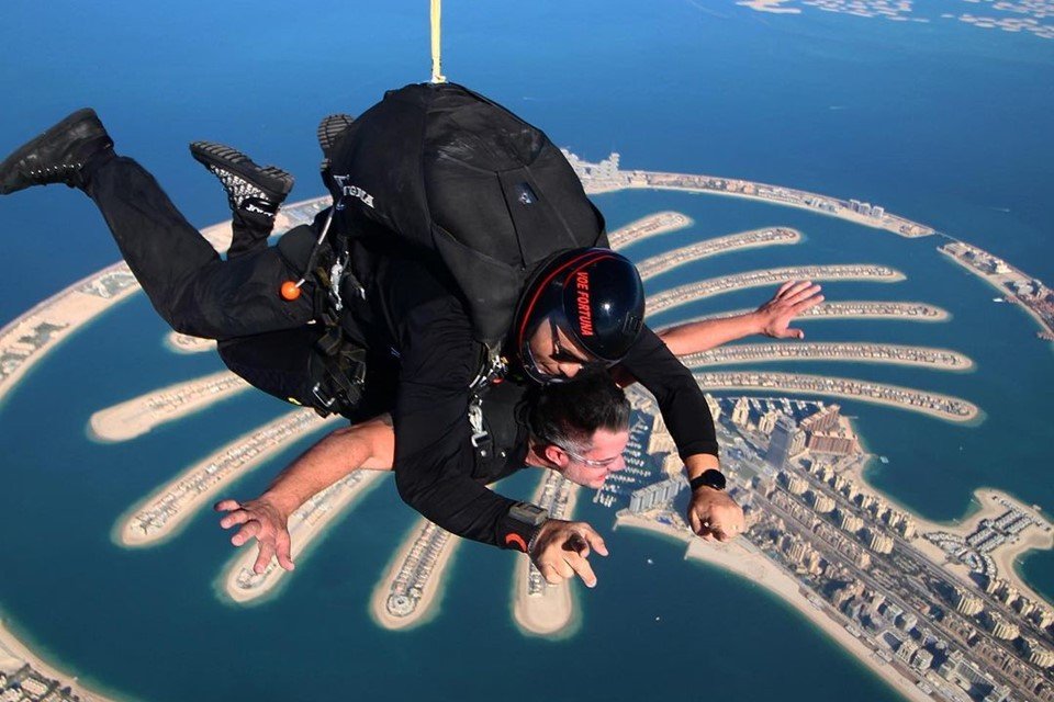 Foto colorida de dois homens saltando de paraquedas em Dubai - Metrópoles