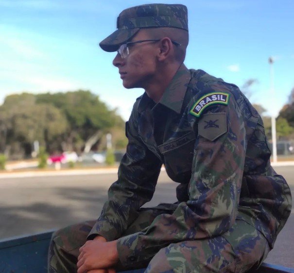 Menino com roupa camuflada do Exército sentado