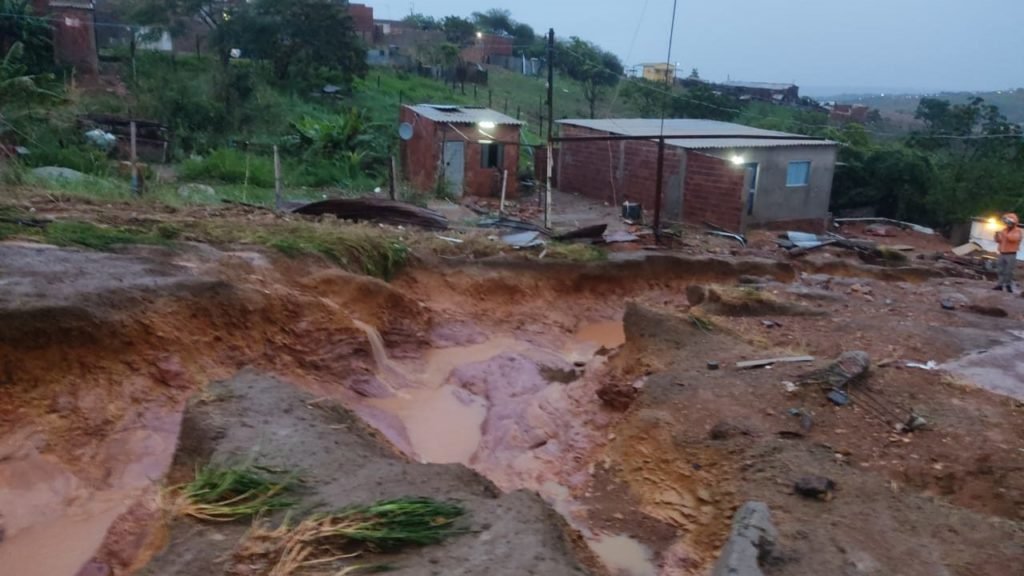 Erosão em chão de barro e casas e tijolo atrás