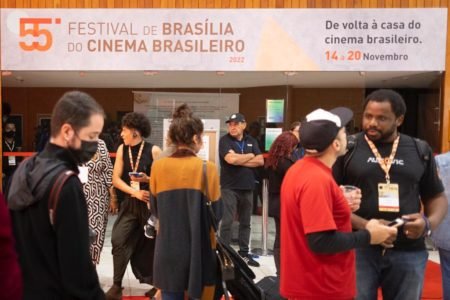 Imagem colorida mostra pessoas em frente ao cartaz do Festival de Cinema de Brasília de 2022 - Metrópoles