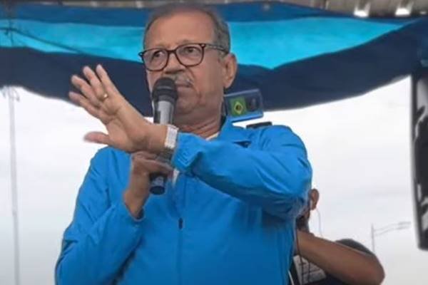 Fotografia colorida de homem com camisa azul segurando microfone