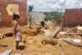 Estrago em casas no Sol Nascente, na Ceilândia, após fortes chuvas.  Na foto vê-se diversos móveis estragados e muita lama em terreno baldio e mulher retraída objetos que ainda não foram danificados - Metrópoles