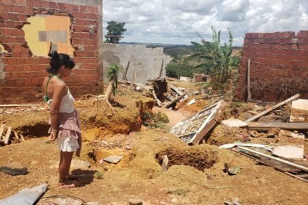 Estrago em casas no Sol Nascente, na Ceilândia, após fortes chuvas. Na foto vê-se diversos móveis estragados e muita lama em terreno baldio e mulher retirado objetos que ainda não foram danificados - Metrópoles