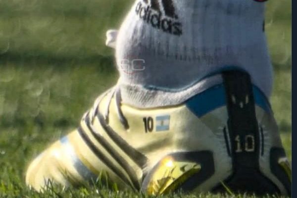 O tornozelo do jogador argentino Lionel Messi em destaque, inchado e com forma circular. Ele usa chuteira amarela - Metrópoles