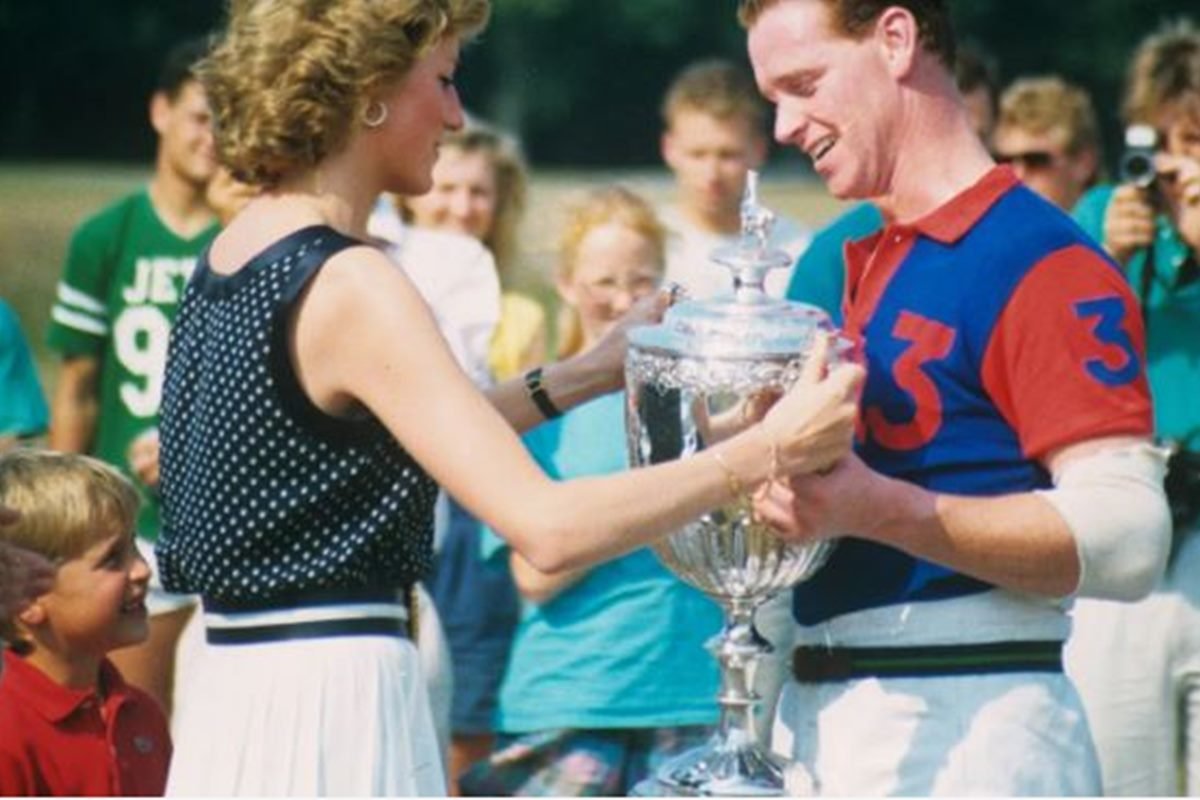 Foto colorida de mulher loira dando um troféu a um homem. Princesa Diana e James-Metrópoles