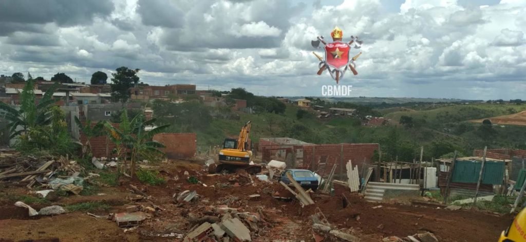 Escavadeira manobra em área afetada pela chuva em Sol Nascente. Chão de terra. Foto colorida