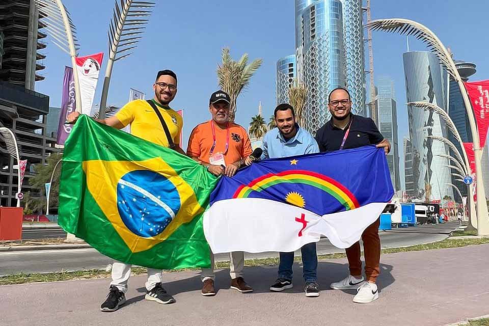 Torcedor pernambucano com a camisa da seleção brasileira posa com jornalistas conterrâneos e a bandeira do estado