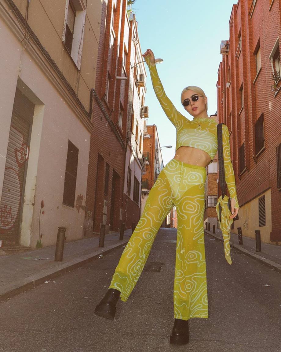 A ex-BBB Jade Picon, uma mulher jovem e branca, posa para foto nas ruas de Paris. Ela usa um conjunto de top e calça estampado verde e branco. O tecido das roupas é ligeiramente transparente. - Metrópoles