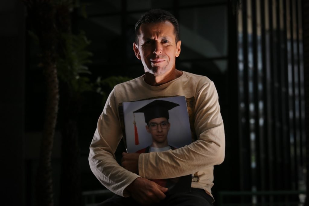 Emocionado e abraçado a uma fotografia do filho, Wilson Ferreira Duarte, 51 anos
