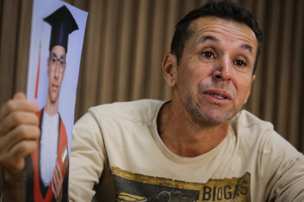 Emocionado e abraçado a uma fotografia do filho, Wilson Ferreira Duarte, 51 anos