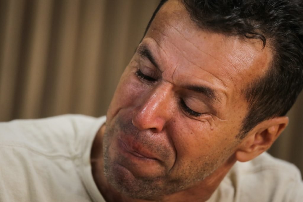 Emocionado e abraçado a uma fotografia do filho, Wilson Ferreira Duarte, 51 anos