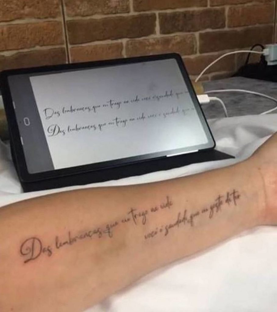 antebraço com frase Das lembranças que trago na vida, você é saudade que eu gosto de ter sobre bancada onde também está um tablet com a mesma frase na tela- metrópoles