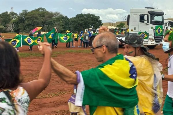 Foto de pessoas de mãos dadas com bandeira do Brasil