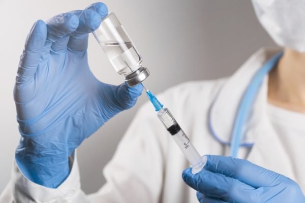Imagem colorida: enfermeira usando luvas azuis preparam vacina - Metrópoles