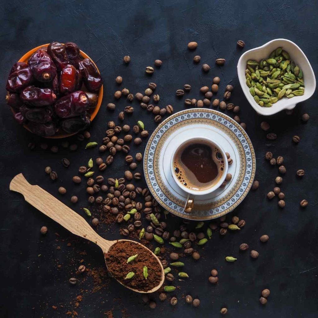 Na foto, grãos de café e especiarias em um fundo cinza e uma xícara com café no meio- Metrópoles