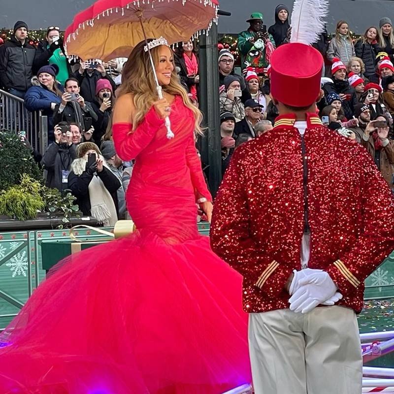 Mariah Carey de vestido vermelho segurando sombrinha e microfone - metrópoles